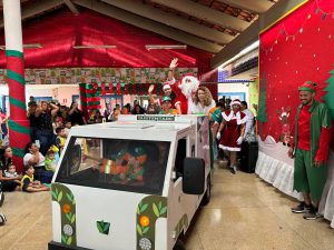 Papai Noel entrega presentes em creche pública sobre minicaminhão compactador
